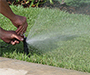 Two hands adjusting an irrigation nozzle.